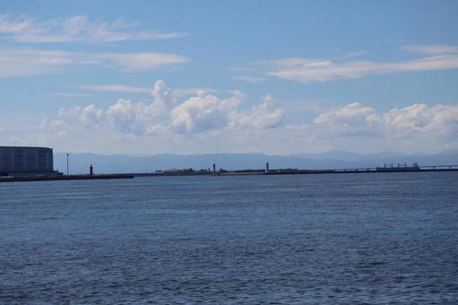 青い海と人工島と船と霞む山並みと雲と青空の写真