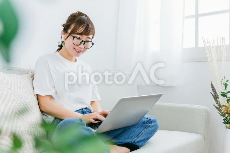 イヤホンを使いながらパソコンを使う女性 パソコン,大学生,動画の写真素材