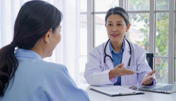 患者女性に説明する日本人医師 患者女性に説明する日本人医師の写真