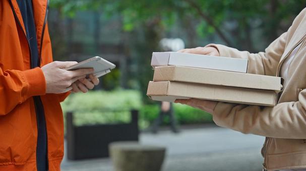 屋外でピザのデリバリーを受け取る女性とタブレットを持っている配達員 配達,フードデリバリー,デリバリーの写真素材