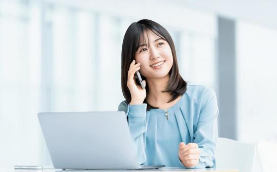 パソコンを使いながらスマホで話す女性 パソコンを使いながらスマホで話す女性 女性,パソコン,スマホの写真素材