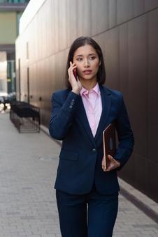 街なかを電話しながら歩いている女性 ビジネスウーマン,ビジネス,女性の写真素材
