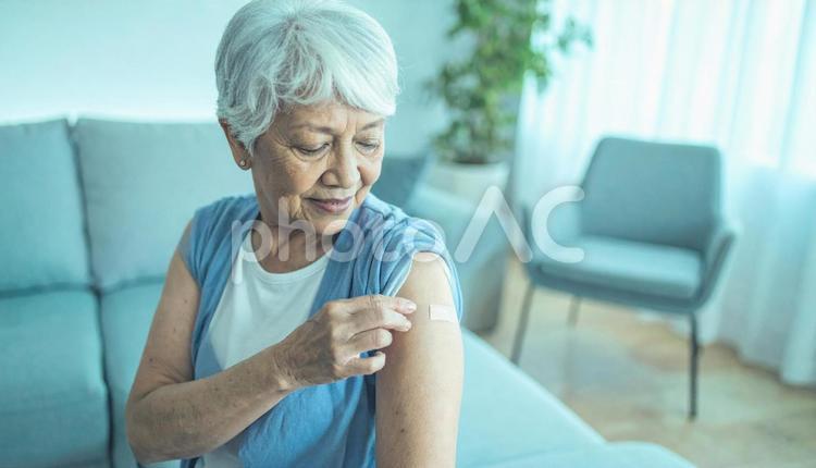 居間で絆創膏を自分の腕に貼る高齢女性患者 絆創膏,シニア女性,ケガの写真素材