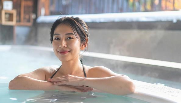温泉につかってリラックスする若い女性 温泉につかってリラックスする若い女性の写真