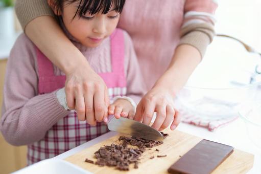お菓子作りをするエプロン姿の女の子と大人 女の子,チョコレート,包丁の写真素材