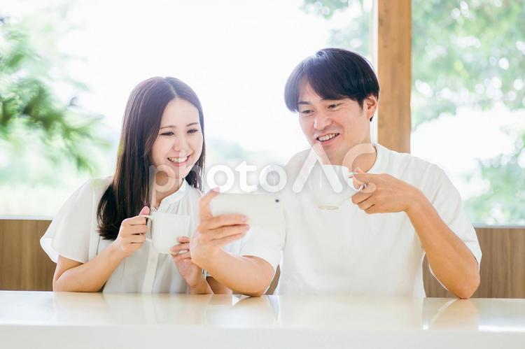 ダイニングでスマホを使う男女 スマホ,夫婦,スマートフォンの写真素材