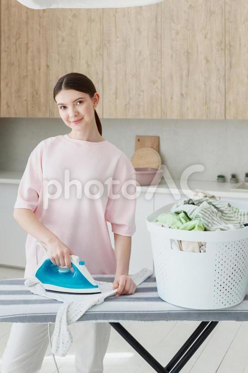 カメラ目線でアイロンする女性の縦写真 女性,人物,立つの写真素材