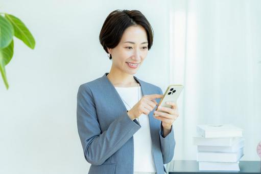 スマホを操作するビジネスウーマン スマホを操作するビジネスウーマン スマホ,笑顔,ミドルの写真素材