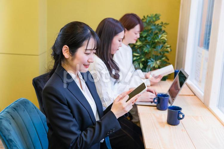 カフェの窓際カウンター席にいる女性（スマホを見る） スマホ,検索,アプリの写真素材