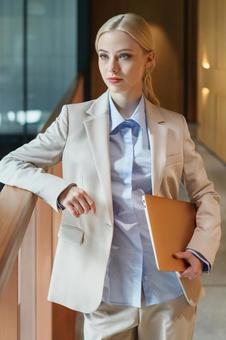 オフィスの廊下の手すりに肘をかけて立つビジネスウーマン ビジネスウーマン,ビジネス,女性の写真素材