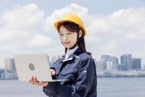 ノートパソコンを使う作業服を着た若い女性 ノートパソコンを使う作業服を着た若い女性 女性,人物,ビジネスウーマンの写真素材