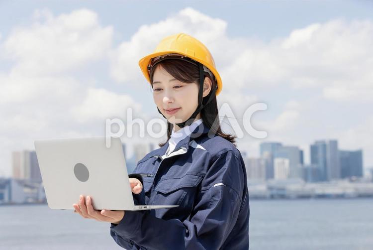 ノートパソコンを使う作業服を着た若い女性 女性,人物,ビジネスウーマンの写真素材