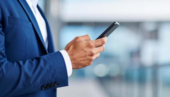 屋外でスマホを操作するビジネスマンの手元 屋外でスマホを操作するビジネスマンの手元の写真