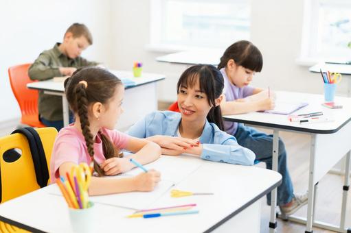 しゃがんで女の子と話す先生 女性,女の子,男の子の写真素材