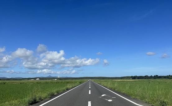 田園地帯にまっすぐ伸びる車道と青空 田園地帯にまっすぐ伸びる車道と青空の写真