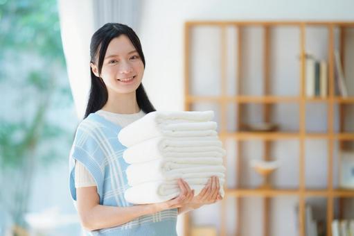 綺麗に畳まれたタオルを持つ笑顔の女性 女性,日本人,タオルの写真素材