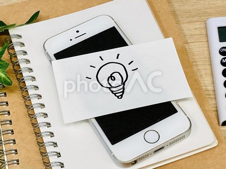 豆電球の絵が書かれたメモとスマホ スマホ,アイデア,豆電球の写真素材