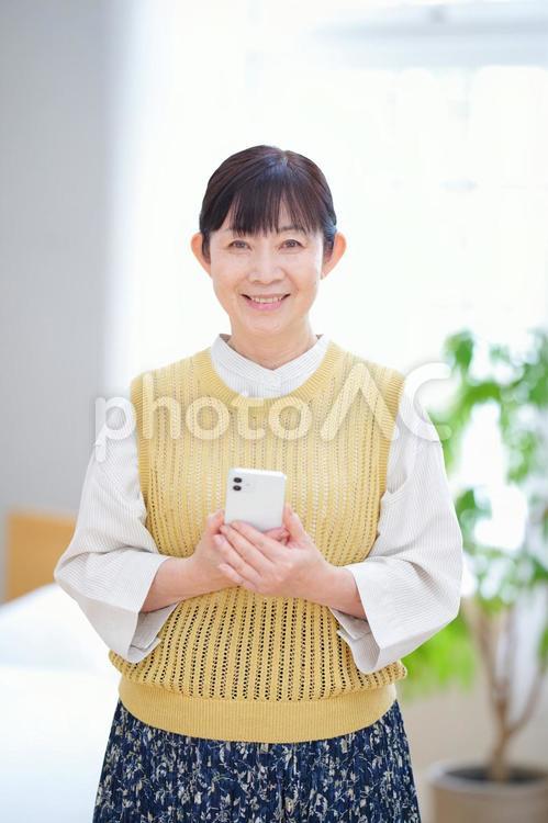 スマホを持つ中年女性のやさしい笑顔 主婦,家政婦,シニアの写真素材
