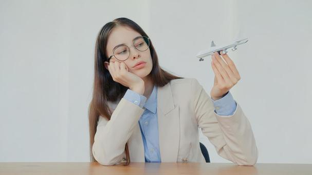飛行機の模型をもって頬杖をつく女性スタッフ 事務職,接客業,アドバイザーの写真素材