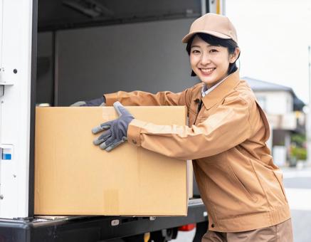 トラックから荷物を出す宅配女性ドライバー トラックから荷物を出す宅配女性ドライバーの写真