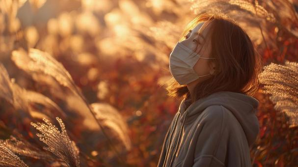 秋風に揺れるススキとマスク姿の女性 秋風に揺れるススキとマスク姿の女性の写真