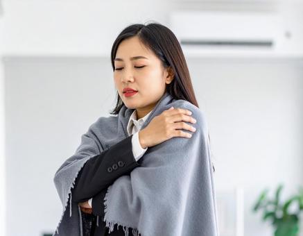 クーラーによる冷え性と戦う女性の写真