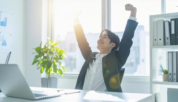 仕事が終わり達成感で背伸びをする社員 仕事が終わり達成感で背伸びをする社員の写真