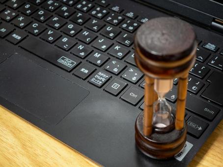 ノートPCと砂時計、時間の流れ ノートパソコン,pc,キーボードの写真素材