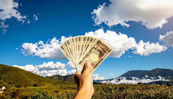 一万円を持つ手 青空背景 一万円を持つ手 青空背景の写真