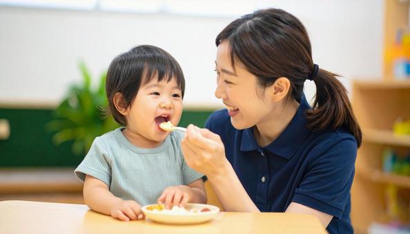 子どもにご飯をあげる保育士 子どもにご飯をあげる保育士の写真