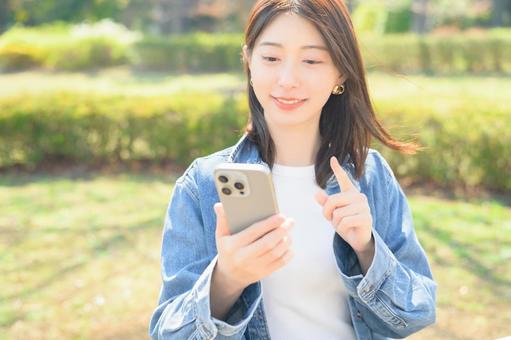 スマホを指差す女性 スマホを指差す女性の写真