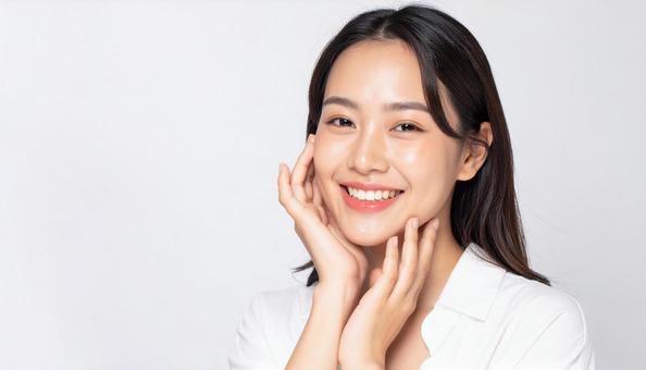 両頬を触り夏のスキンケアをする20代女性の写真