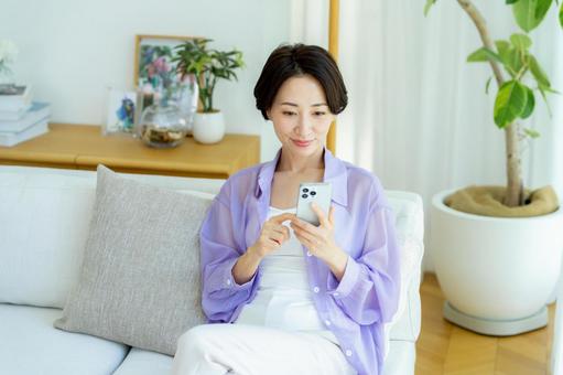 部屋でスマホを使うミドル女性 スマホ,笑顔,女性の写真素材