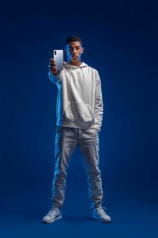 スマートフォンを構えるクールな若者 スマートフォンを構えるクールな若者の写真
