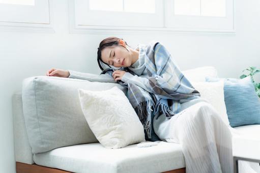 ソファで寝る女性 風邪,体調不良,発熱の写真素材