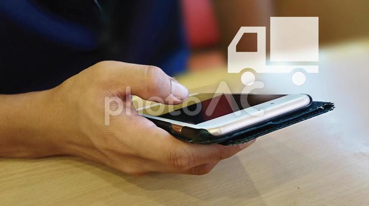 スマホを操作する手と配送トラック スマホ,インターネット,スマートフォンの写真素材