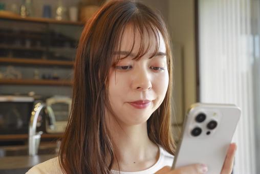 スマートフォンを操作する女性 スマートフォンを操作する女性 女性,横顔,笑顔の写真素材