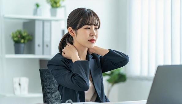 デスクワークで肩こりに悩むビジネスマンの写真