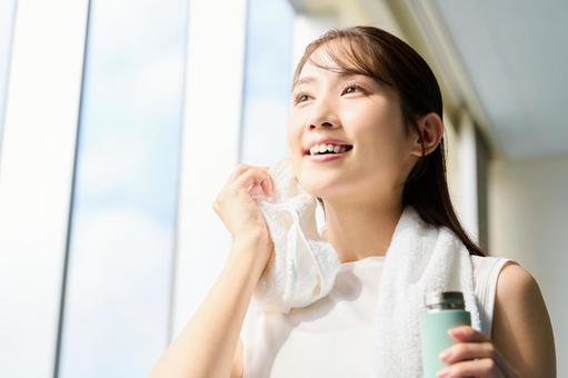 ジムで汗を拭く笑顔の女性 スポーツジム,運動後,水分補給の写真素材