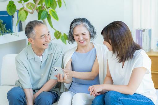 リビングでスマホを見るシニア夫婦と子供 シニア,夫婦,スマホの写真素材