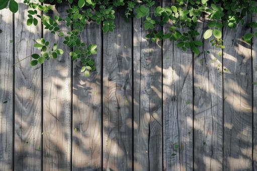 木漏れ日が映る木のフェンスと緑の葉 木漏れ日が映る木のフェンスと緑の葉の写真