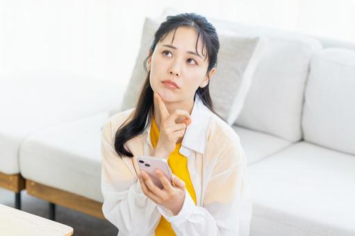 スマホを持って考える若い女性 スマホを持って考える若い女性 スマホ,困る,悩むの写真素材