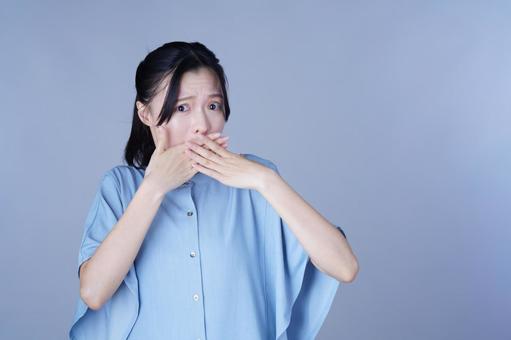 口を両手を抑える青い服の女性 女性,口を隠す,内緒の写真素材
