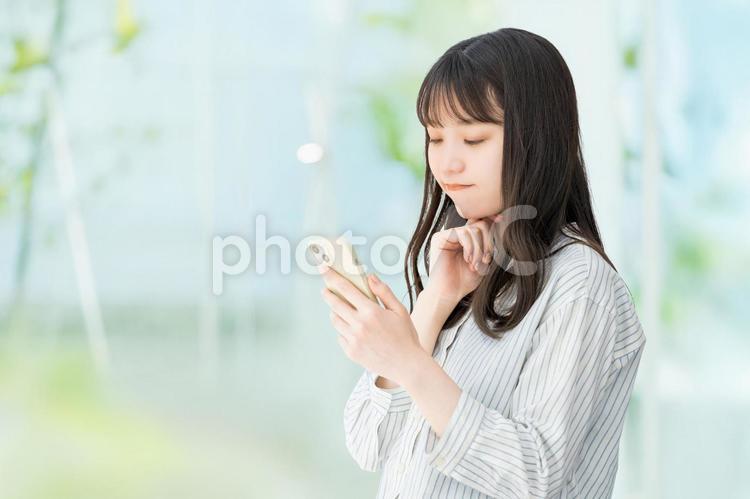 スマホを見て考える女性・ビジネスウーマン 女性,スマホ,考えるの写真素材