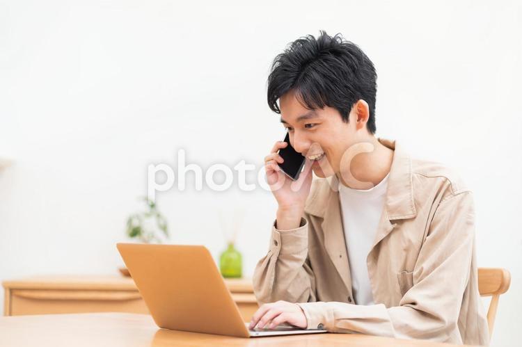 パソコン作業をしながら電話をする男性 男性,ビジネスマン,学生の写真素材