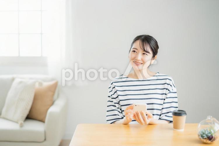 テーブルでスマホを使う女性（笑顔） スマホ,アプリ,女性の写真素材