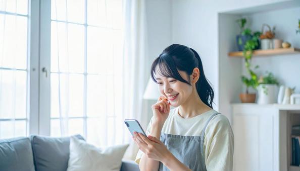スマホでポイ活する笑顔の女性 スマホでポイ活する笑顔の女性の写真