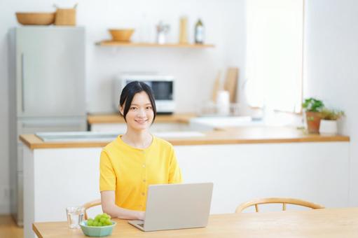 ダイニングでパソコンをするカメラ目線の女性 女性,ノートパソコン,座るの写真素材