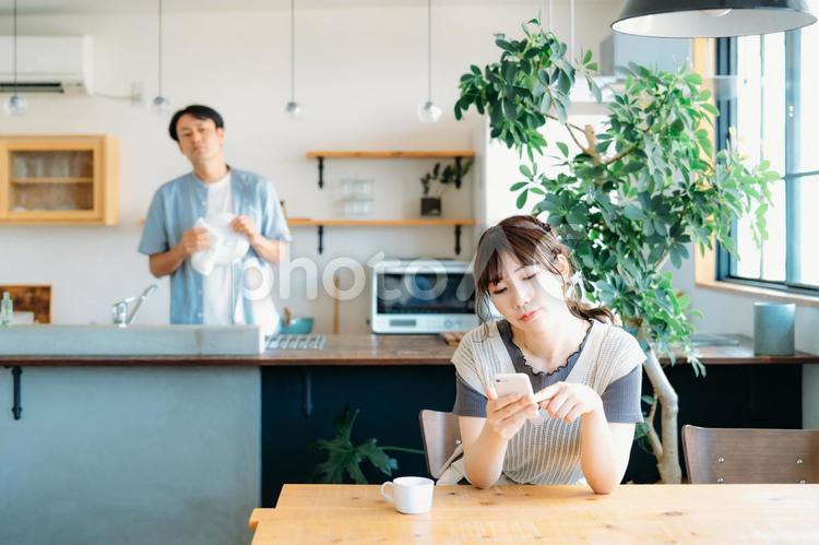 スマホを見る女性と疑う男性（退屈） スマホ,退屈,不倫の写真素材