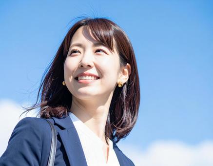 青空の下歩くビジネスウーマン 青空の下歩くビジネスウーマンの写真